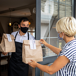 masked woman picking up take-out at restaurant